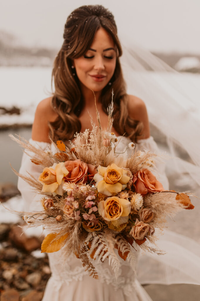A bride holding a terracotta, golden mustard, toffee, pampas wedding bridal bouquet. 